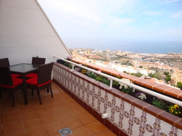 Apartment terrace with a table and chairs looking out over a town to the sea in Tenerife